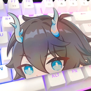 May include: A sticker of an anime character with blue hair and horns. The character has blue eyes and is looking to the right. The sticker is placed on a white keyboard with blue backlighting.