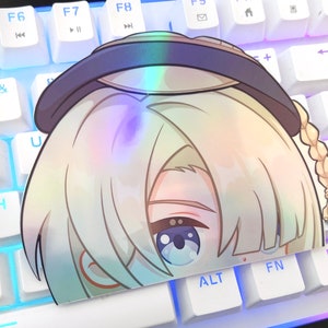 May include: A holographic sticker featuring a cartoon character with blonde hair, blue eyes, and a braid. The character is wearing a black hat with a white brim.