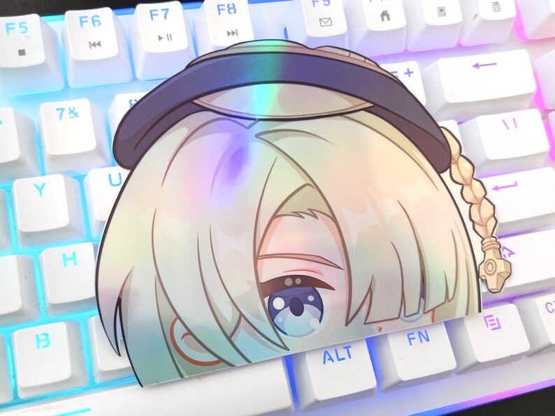 May include: A holographic sticker featuring a cartoon character with blonde hair, blue eyes, and a braid. The character is wearing a black hat with a white brim.