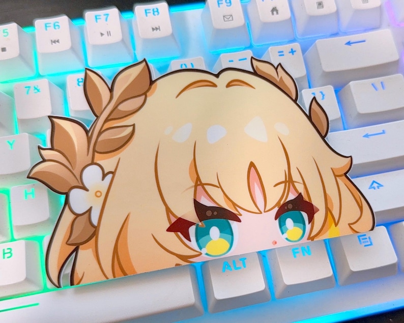 May include: A die-cut sticker featuring an anime-style character with blonde hair and teal eyes. The sticker is partially obscuring a white keyboard, with the character's face peeking over the keys. The sticker has a floral crown.