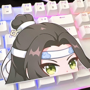 Peut inclure: Un autocollant représentant un personnage d'anime avec de longs cheveux bruns, portant un bandeau blanc avec des nuages bleus, qui dépasse d'un clavier blanc.