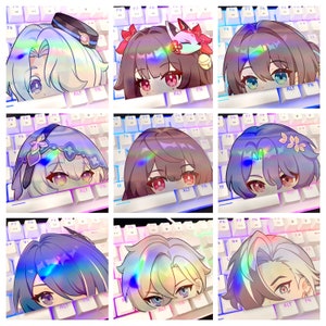 May include: Nine holographic stickers featuring anime-style character faces peeking over a white keyboard. Each sticker has a unique hair color and design, with vibrant rainbow reflections. The keyboard has colorful LED lights.