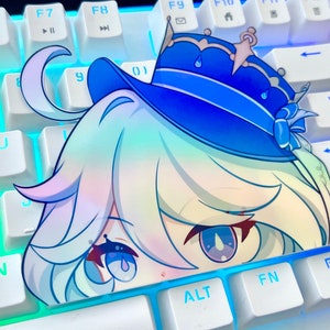 May include: A sticker of a cartoon character with blue hair, blue eyes, and a blue hat with a crown on top. The sticker is placed on a white keyboard with blue backlighting.