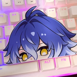 May include: A sticker of an anime-style character with blue hair and yellow eyes, placed on a white keyboard. The keyboard has purple backlighting, illuminating the keys. The sticker partially obscures the view.