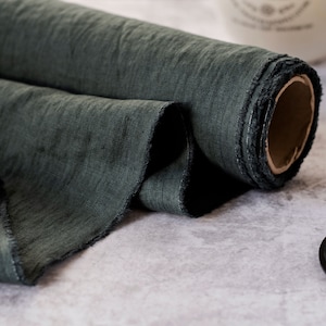Pu&ograve; includere: Un rotolo di tessuto di lino verde scuro con un bordo grezzo e sfilacciato. Il tessuto ha un aspetto strutturato. Il rotolo &egrave; parzialmente srotolato, mostrando il nucleo di cartone interno. Ideale per progetti di cucito e artigianato.