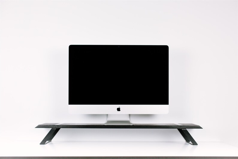 May include: A black metal monitor stand with a white computer monitor on top. The monitor has a black screen and a silver Apple logo.