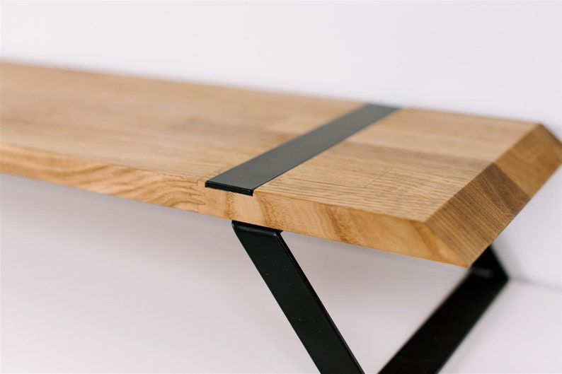 May include: A wooden shelf with a black metal bracket. The shelf has a black metal strip running across the top.