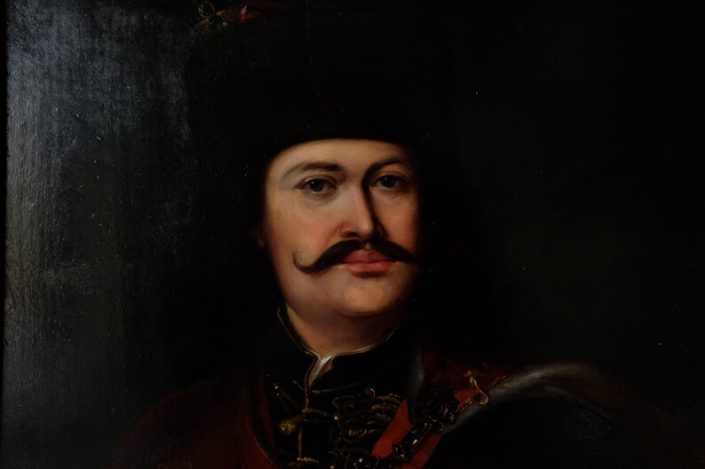 May include: A portrait painting of a man with a dark mustache and a black hat. He is wearing a dark jacket with gold accents and a red sash.