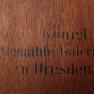 May include: A close-up of a wooden surface with black ink stamped text that reads "Innung:  Deutsche  Industrie  in Dresden."