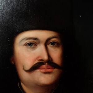 May include: A close-up portrait painting of a man with a dark mustache and a black hat. The man has a light complexion and blue eyes. The painting is done in a realistic style.
