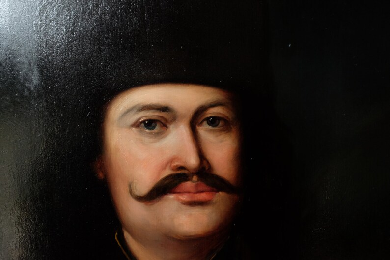 May include: A close-up portrait painting of a man with a dark mustache and a black hat. The man has a light complexion and blue eyes. The painting is done in a realistic style.