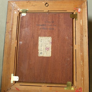 May include: A wooden picture frame with a black border. The back of the frame has a label that reads "Kunstgewerbe-Galerie in Dresden." and "Emil Glog Nachf. Dresden, Germany."
