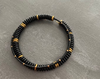 May include: A black and gold beaded bracelet with a double-wrap design.