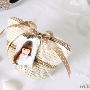 May include: A small crocheted pouch with a zipper closure, decorated with a brown and white polka dot ribbon and a framed photo of a young girl. The pouch is made with a beige and brown yarn.
