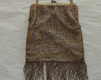 Peut inclure: Un sac à main rectangulaire en perles avec un motif métallique doré et argenté. Le sac possède un cadre en métal articulé avec une fermeture à fermoir, une fine bandoulière en chaîne métallique et une longue frange de perles pendantes.