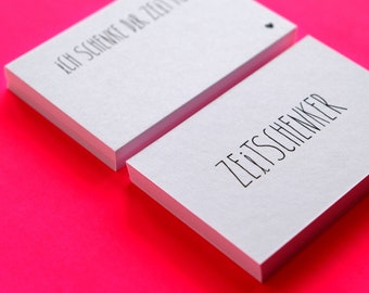May include: Two stacks of white rectangular cards with black text on a bright pink background. The top card of the first stack reads "ICH SCHENKE DIR ZEIT FUR" and the top card of the second stack reads "ZEITSCHENKER".
