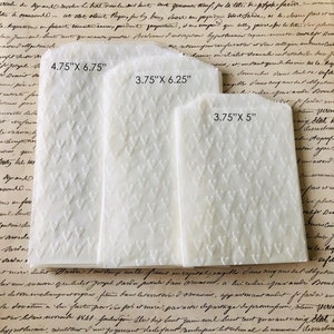 May include: Three white envelopes with a heart pattern embossed on the surface. The envelopes are different sizes: 4.75" x 6.75", 3.75" x 6.25", and 3.75" x 5".