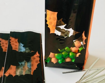 May include: Black and orange Halloween treat bags with bat silhouettes. The bags are filled with green and orange candies. Silver twist ties are scattered nearby. The bags are perfect for Halloween party favors.