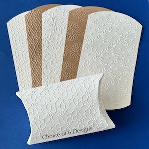 May include: Six different designs of white and brown pillow boxes with embossed patterns. The boxes are arranged in a fan shape with the text "Choice of 6 Designs" printed on the bottom box.