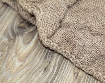 May include: Close-up of a brown burlap fabric with a woven texture. The fabric has a rough, natural look and feel.