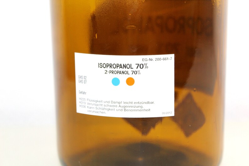 Puede incluir: Una botella de vidrio marr&oacute;n con una etiqueta blanca que dice "ISOPROPANOL 70% 2-PROPANOL 70%". La etiqueta tambi&eacute;n incluye el texto "GHS 02 GHS 07 EG-Nr. 200-661-7" e informaci&oacute;n de seguridad en alem&aacute;n.