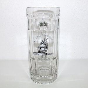 May include: A clear glass beer stein with a printed design of a ship and the text "Hamburger  Deernties" and "Reeperbahn".