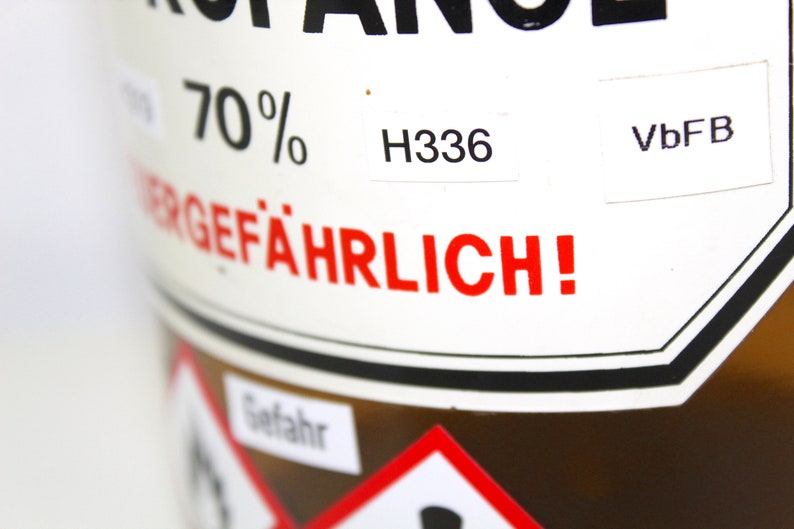 Puede incluir: Una botella de vidrio marr&oacute;n con una etiqueta blanca que dice "70% GEF&Auml;HRLICH!" y "H336" y "VbFB".