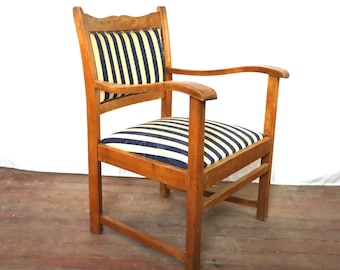 Könnte beinhalten: Ein Holzsessel mit einem gestreiften Stoffbezug für Sitzfläche und Rückenlehne. Der Sessel hat eine geschwungene Armlehne und ein schlichtes Design.