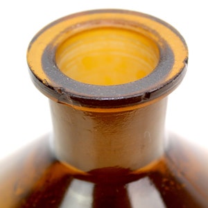 Puede incluir: Primer plano de la parte superior de una botella de vidrio marr&oacute;n con una abertura de boca ancha.