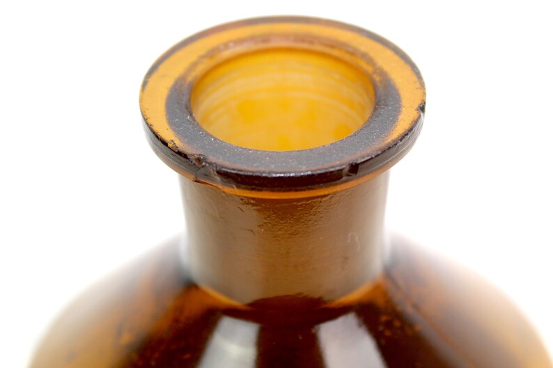 Puede incluir: Primer plano de la parte superior de una botella de vidrio marr&oacute;n con una abertura de boca ancha.