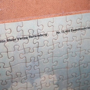 K&ouml;nnte beinhalten: Ein blaues Puzzle mit dem Text "Otto Maier Verlag Ravensburg Nr. 15.455 Seeschlacht bei Lissa" darauf gedruckt.