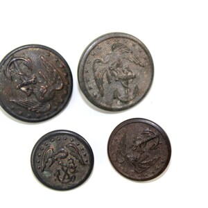 Könnte beinhalten: Vier vintage Metallknöpfe mit Adler- und Ankerdesign. Die Knöpfe sind dunkelbraun und haben einen abgenutzten Look.