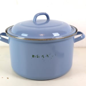 Op de afbeelding: Een lichtblauwe emaille pan met twee handvatten en een deksel. De pan heeft een zilveren rand en een groene inscriptie met de tekst "BEKA" op de bodem.