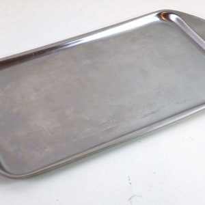 Könnte beinhalten: Ein silbernes Serviertablett mit abgerundeten Kanten und einer glatten Oberfläche.