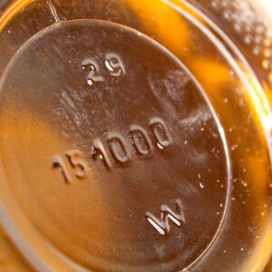 Puede incluir: Primer plano de una botella de vidrio marr&oacute;n con una etiqueta que dice "29 151000 W".