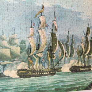 K&ouml;nnte beinhalten: Ein Vintage-Puzzle, das eine Seeschlacht mit mehreren Segelschiffen im Ozean darstellt. Die Schiffe haben wei&szlig;e Segel und feuern Kanonen aufeinander ab. Der Himmel ist blau und bew&ouml;lkt.