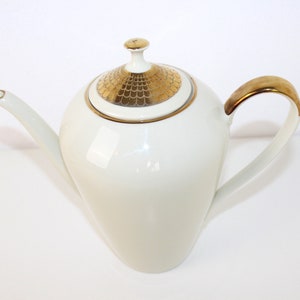 May include: White porcelain coffee pot with a gold-trimmed lid and handle. The lid has a geometric pattern in gold.