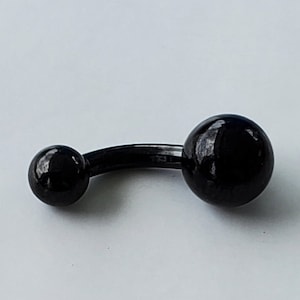 May include: A black belly button ring with two round, glossy black balls connected by a curved bar. The jewelry is set against a white background, highlighting its simple, modern design.