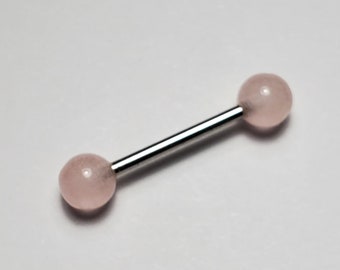 Op de afbeelding: Een zilveren barbell met twee ronde roze kralen. De barbell is een soort lichaamsieraad.