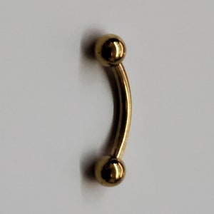 May include: A gold-colored curved barbell with two round balls on each end.