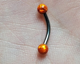 Op de afbeelding: Een zilveren gebogen barbell met twee oranje opaalkogels aan de uiteinden.