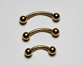 Op de afbeelding: Drie gouden gebogen barbell-lichaamssieraden met baluiteinden.