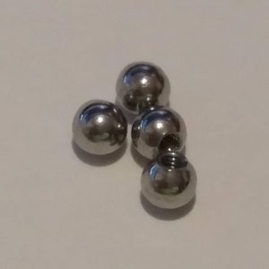 May include: Five silver metal balls, some with threaded holes, for jewelry making or other crafts.