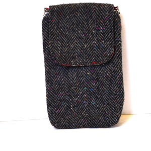 May include: A gray tweed crossbody phone bag with a flap closure and a herringbone pattern. The bag has a red lining and a silver zipper.