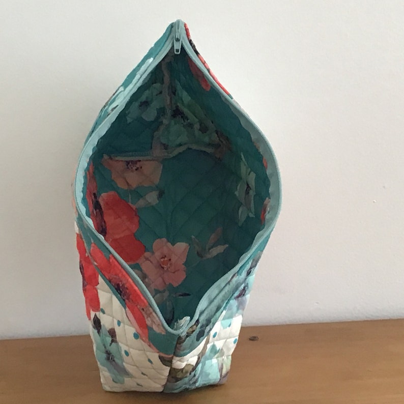 Quilted placemat zipper bag in floral print of teal and orange and exterior scalloped edge