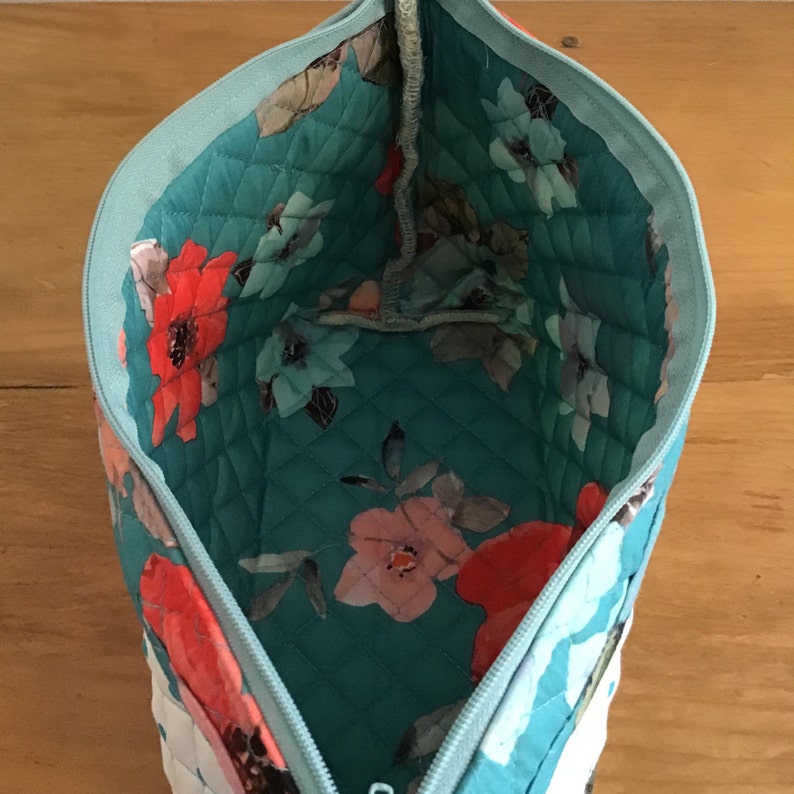 Quilted placemat zipper bag in floral print of teal and orange and exterior scalloped edge