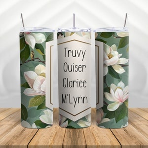 May include: Three stainless steel tumblers with a green and white floral design. The center tumbler has a gold frame with the names "Truvy Ouiser Clariee M'Lynn" written in black.