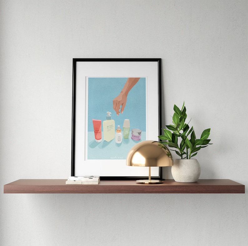 May include: A framed illustration of a hand reaching for a row of five different skincare products on a light blue background. The products include a pink tube, a clear bottle with a pump, a small clear bottle, a green bottle, and a small purple jar. The text "Daily Routine" is written below the products.