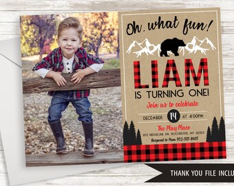 May include: A birthday invitation featuring a photo of a young boy leaning on a wooden fence. The invitation has a kraft paper background with red and black plaid accents and the text "Oh what fun!" and "LIAM IS TURNING ONE!"