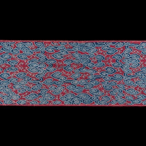 Könnte beinhalten: Ein langes, schmales Stoffband mit rotem Hintergrund und einem blauen und weißen Muster. Das Muster ist ein sich wiederholendes Design aus Wolken und Sternen. Der Stoff hat einen Fransenrand.